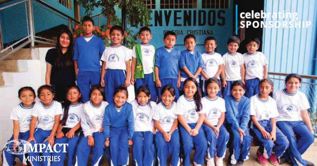 Class Picture of young students wearing blue track pants and white Vida t-shirts or blue sweaters
